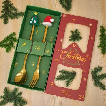 Goudkleurige lepel en vork met kerstmuts en kerstboom in geschenkdoos